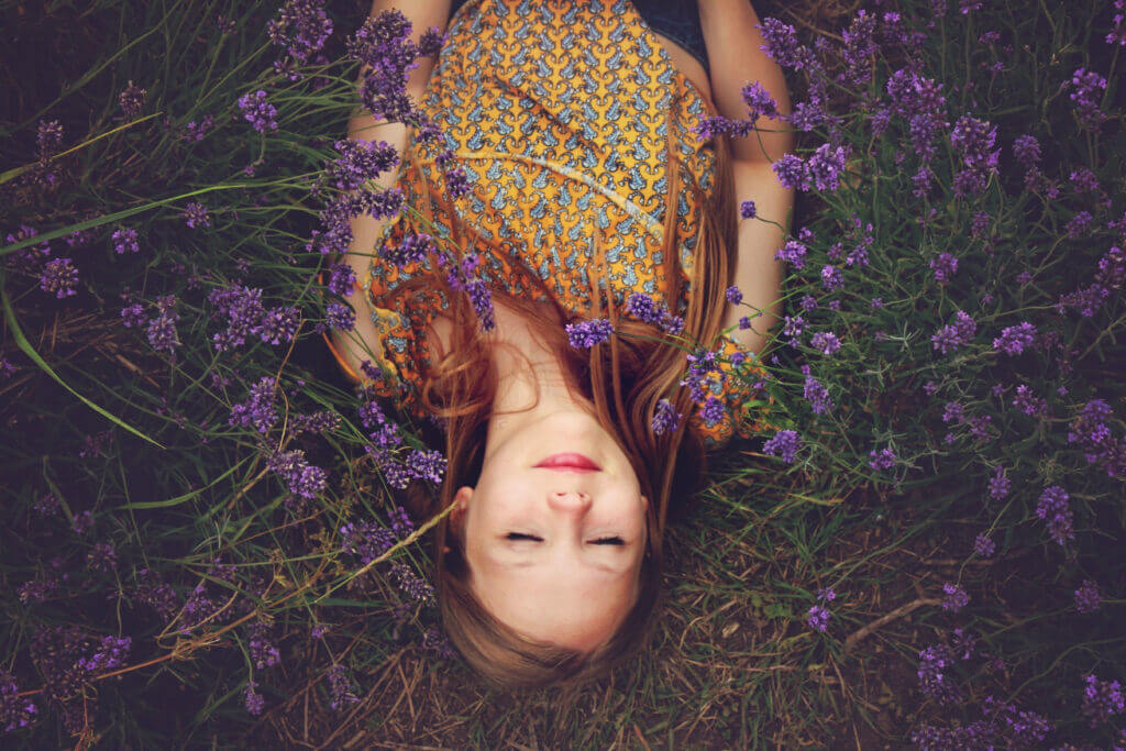 Eine junge Frau liegt im Lavendelfeld.