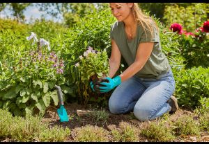 Eine junge Frau trägt bei Pflanzarbeiten die Gardena Pflanz- und Bodenhandschuhe
