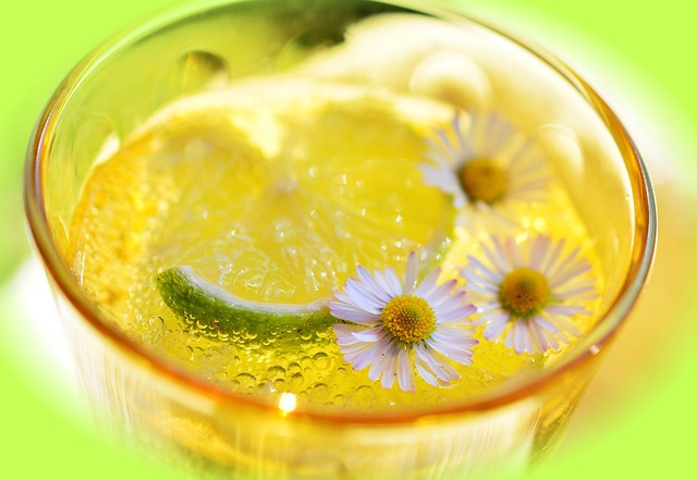 Ein Glas Limonade mit einer halben Limette und drei Gänseblümchen dekoriert.