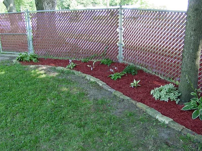 Rindenmulch im Beet zwischen Blumen neben Rasen