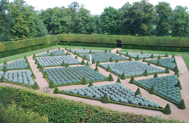 In einem Schloßgarten gedeihen in in 10 großen Beeten zahlreiche Lavendel- und Heiligenkrautbüsche mit einem halbkugeligen Formschnitt.