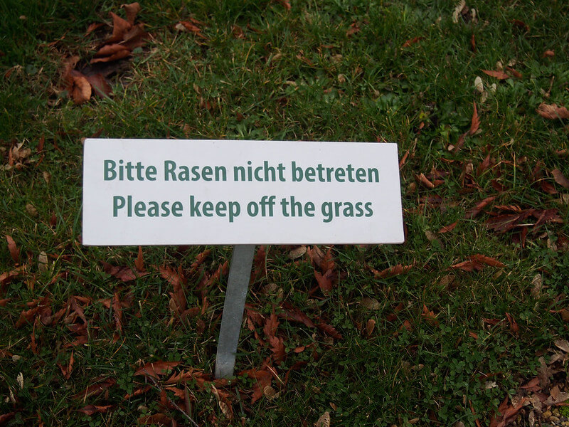 In einem Rasen steckt ein Schild mit Betreten verboten.