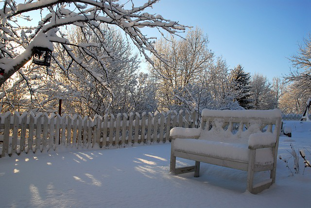 Tief verschneiter Garten mit Gartenbank und ohne Fußspuren im Schnee