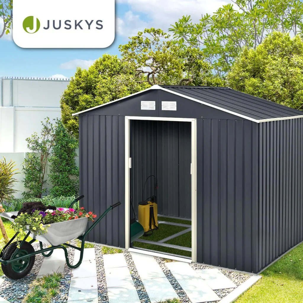 Das Juskys Gerätehaus im Garten mit Schubkarre davor